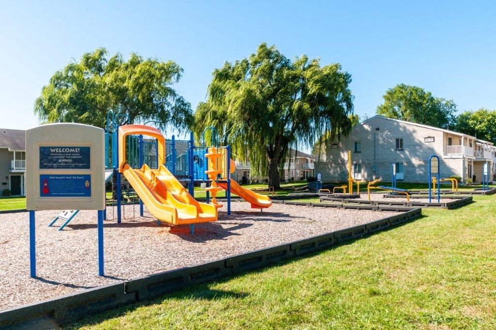 a playground with slides and a sign in a park