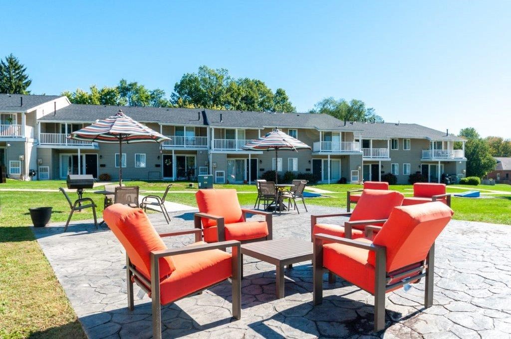 a patio with chairs and umbrellas in front of a building