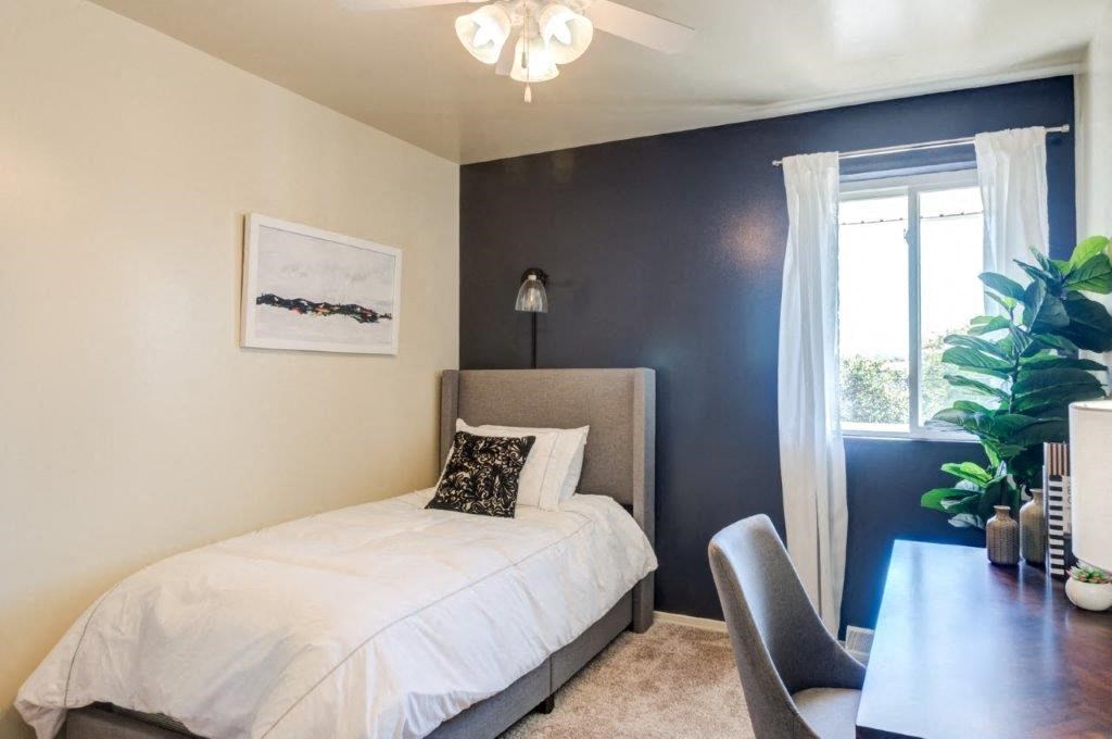 a bedroom with a bed and a desk and a window