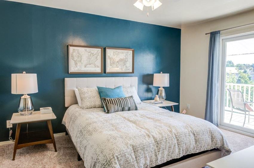 a bedroom with a bed and a blue wall and a window