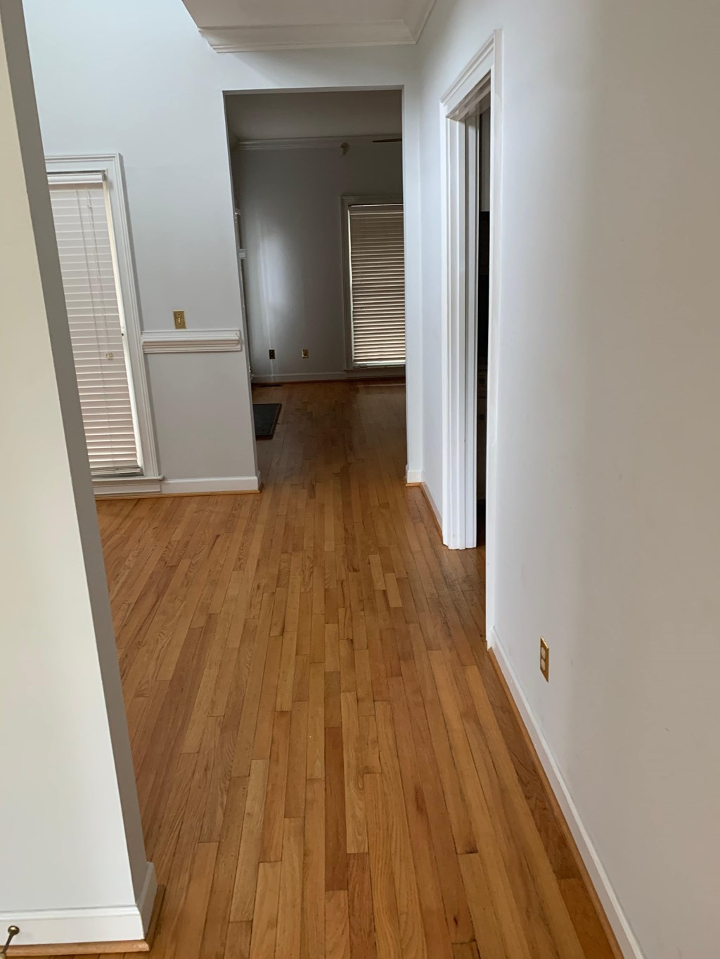 a renovated living room and hallway with wood floors and white walls