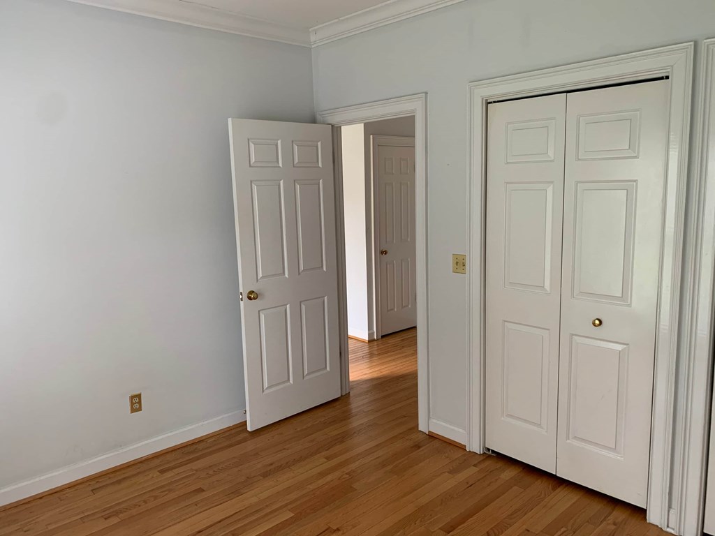 a bedroom with two doors and a hard wood floor