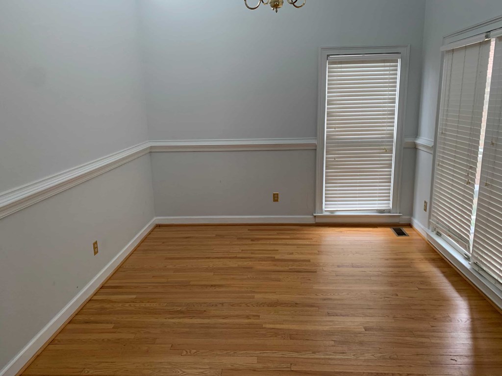 a room with wooden floors and white walls and a window