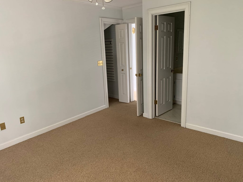 a bedroom with a carpeted floor and a hallway with two doors