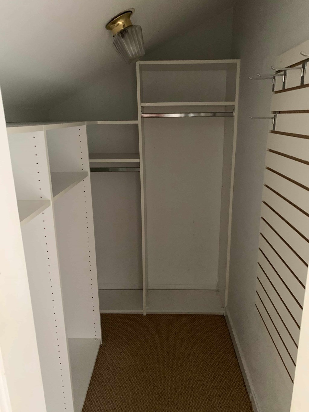 a closet with white shelves and a light on the ceiling