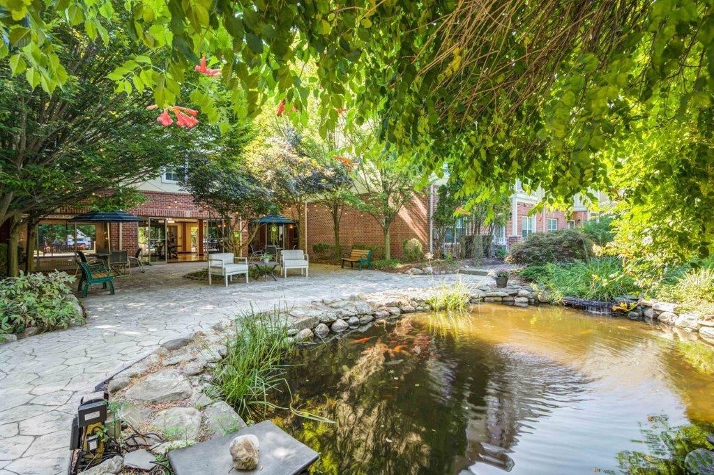 the backyard has a pond and a patio with benches