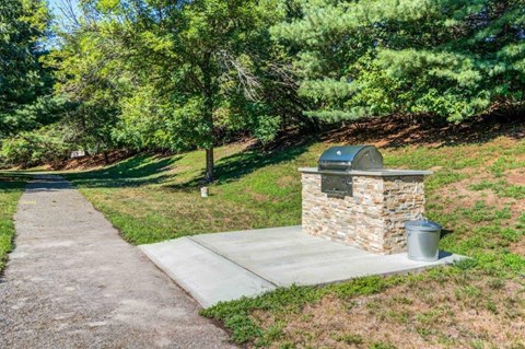a brick smoker in a park next to a sidewalk