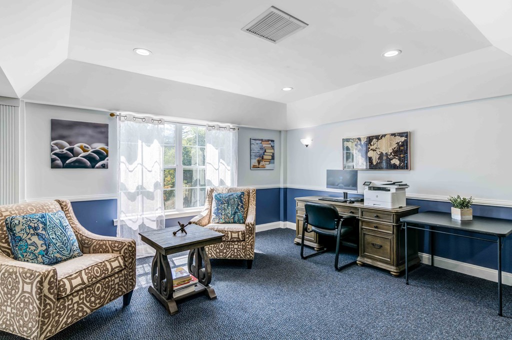 a living room with chairs and a desk and a window