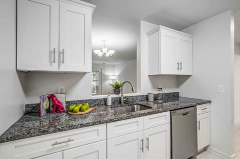 a white kitchen with white cabinets and granite counter top