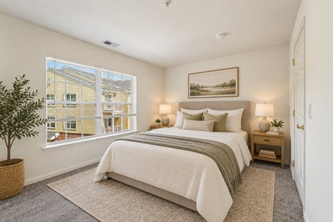 A bedroom with a large bed and a window overlooking a building.