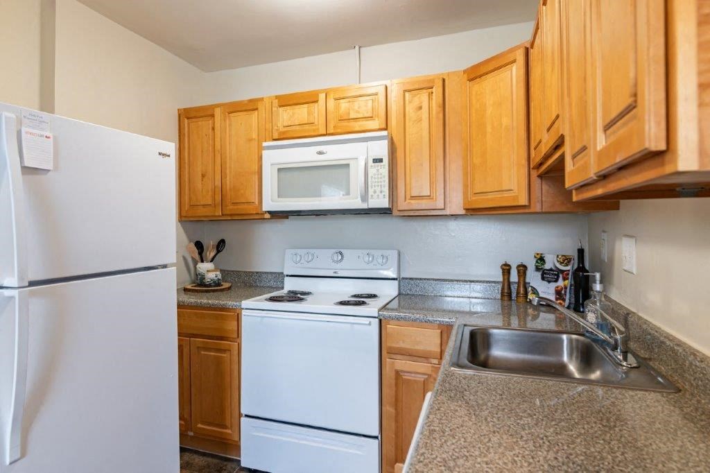 a kitchen with white appliances and wooden cabinets