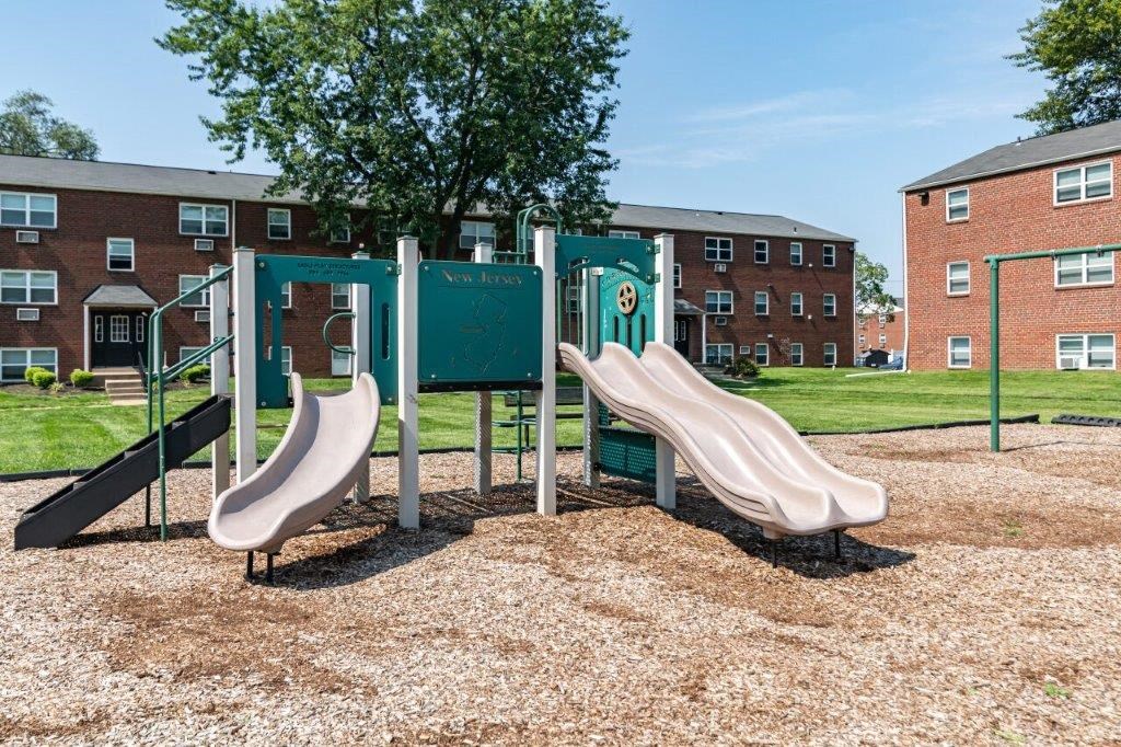 two slides on a playground in front of a building