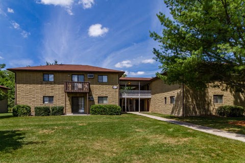 a large brick apartment building with a sidewalk and a tree