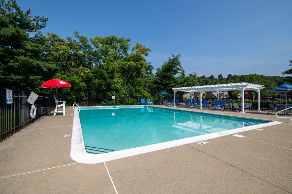 a swimming pool with a red umbrella and chairs around it