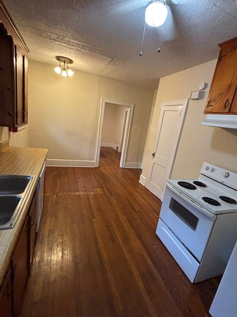 A kitchen with a white stove and wooden floors.