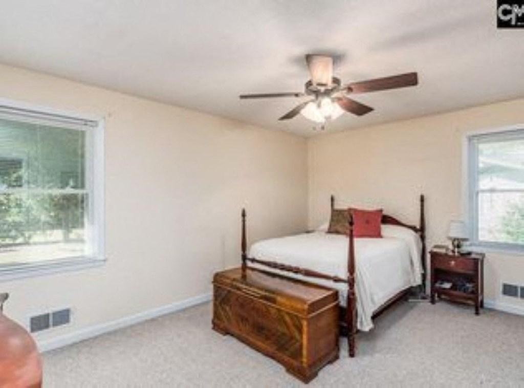 A bedroom with a bed, nightstand, and window.