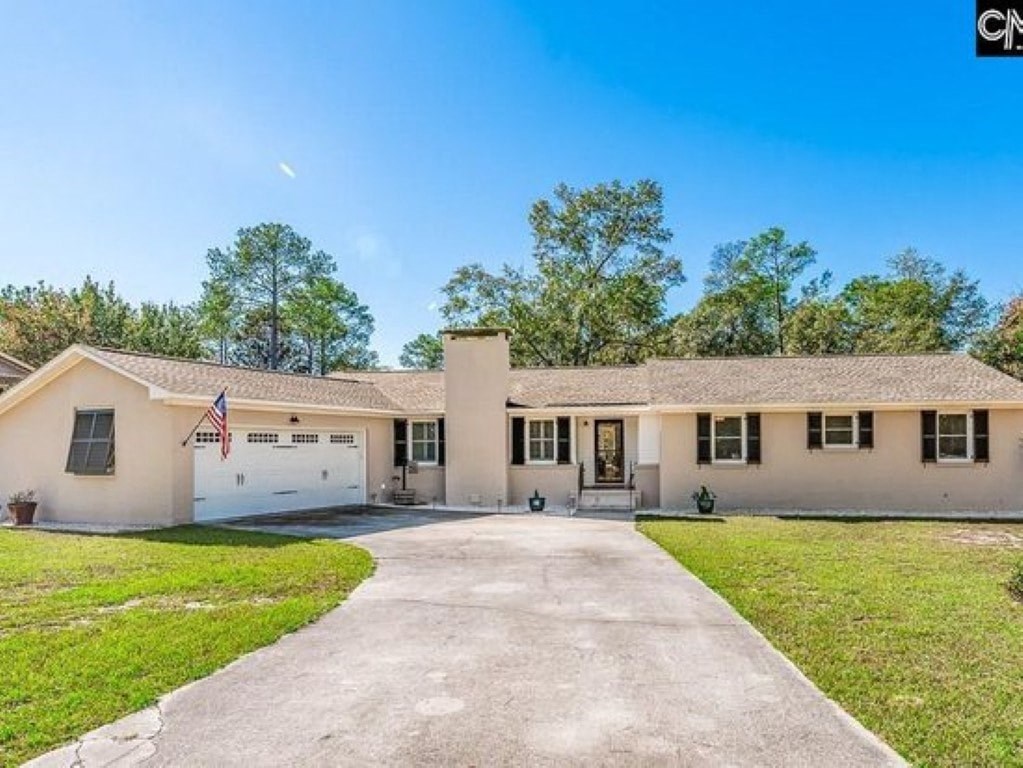 A house with a flag on the front has a driveway leading to the garage.