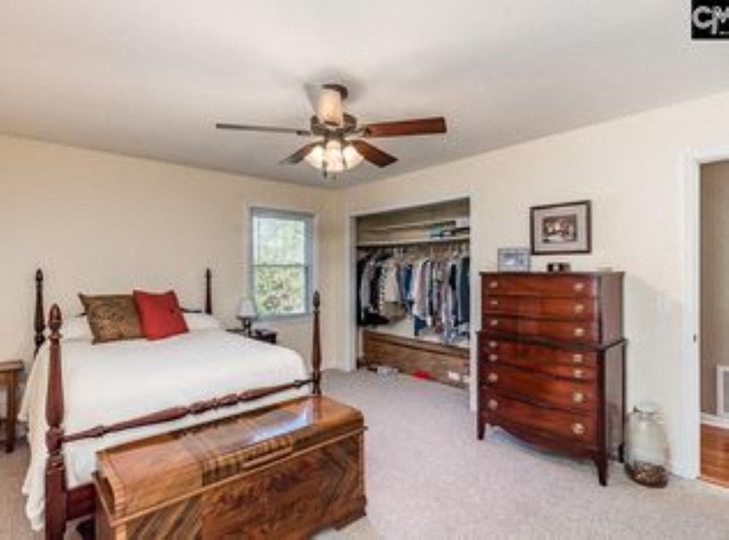 A bedroom with a bed, dresser, and a ceiling fan.