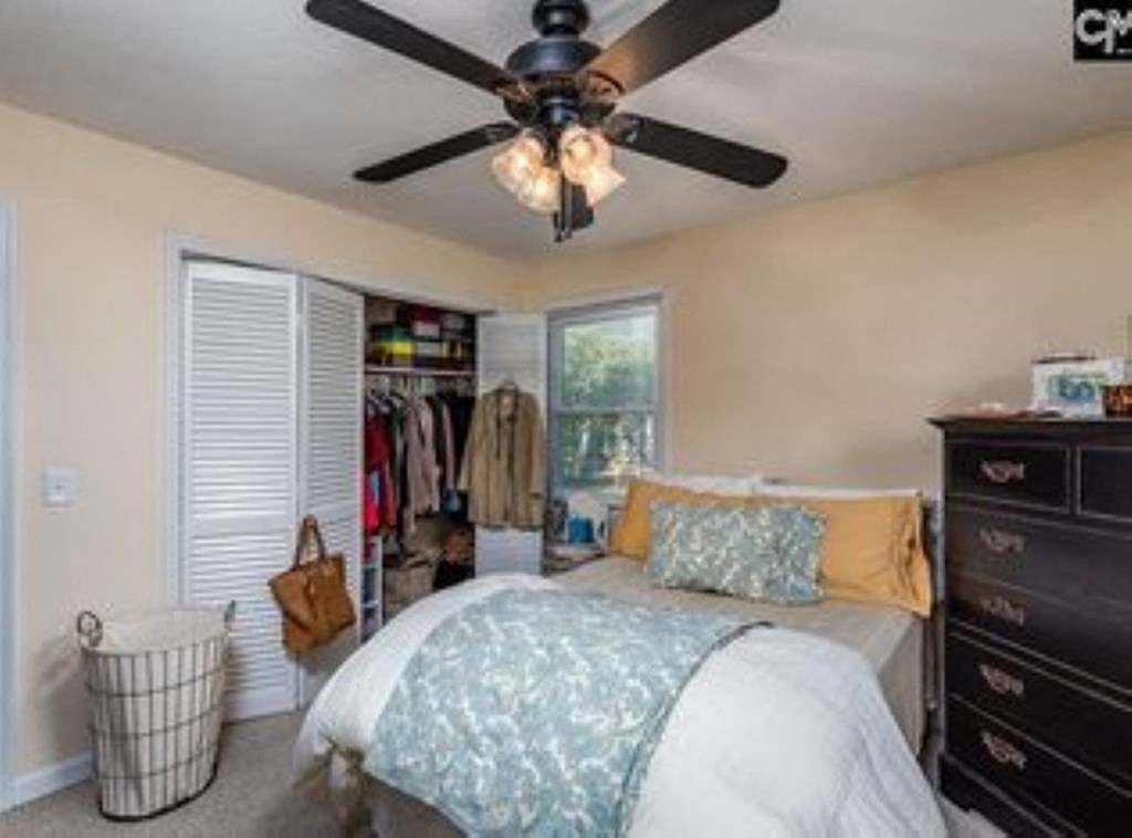 A bedroom with a bed, dresser, and a ceiling fan.