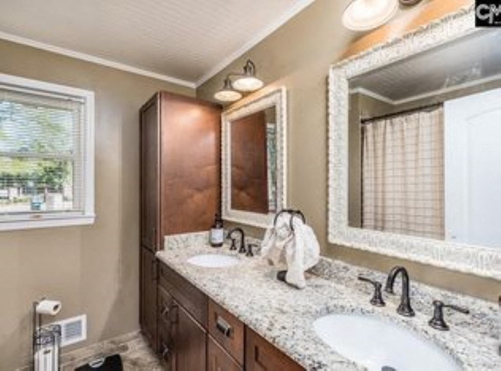 A bathroom with a sink, mirror, and a window.