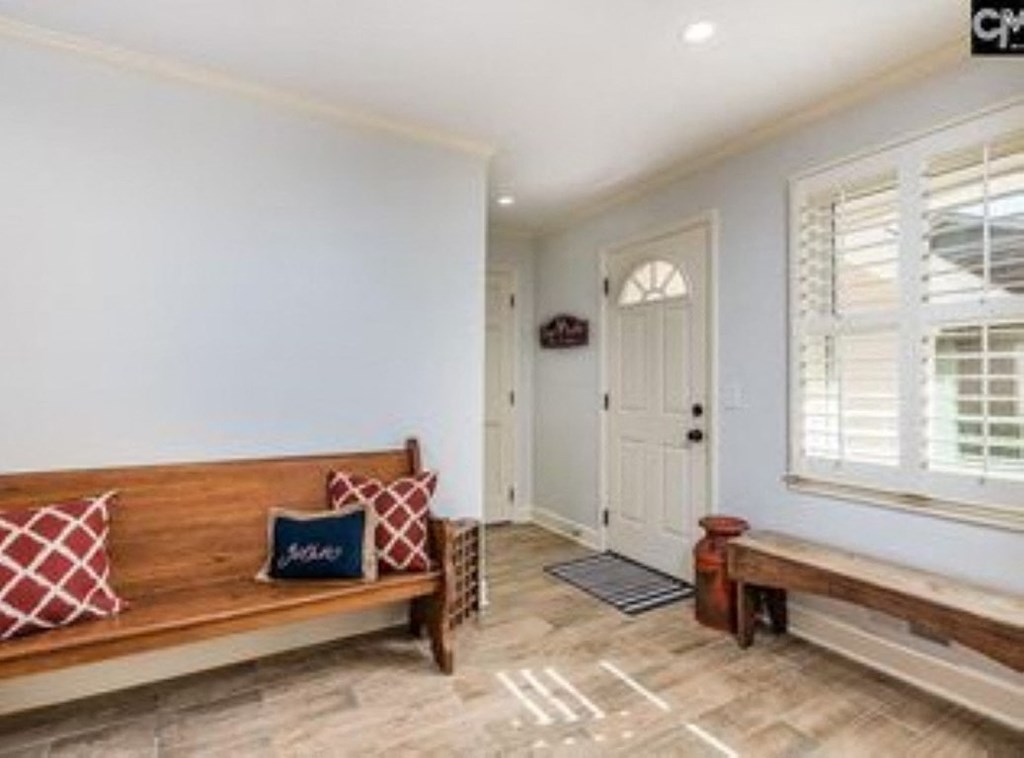 A wooden bench with red and blue pillows sits in a hallway.
