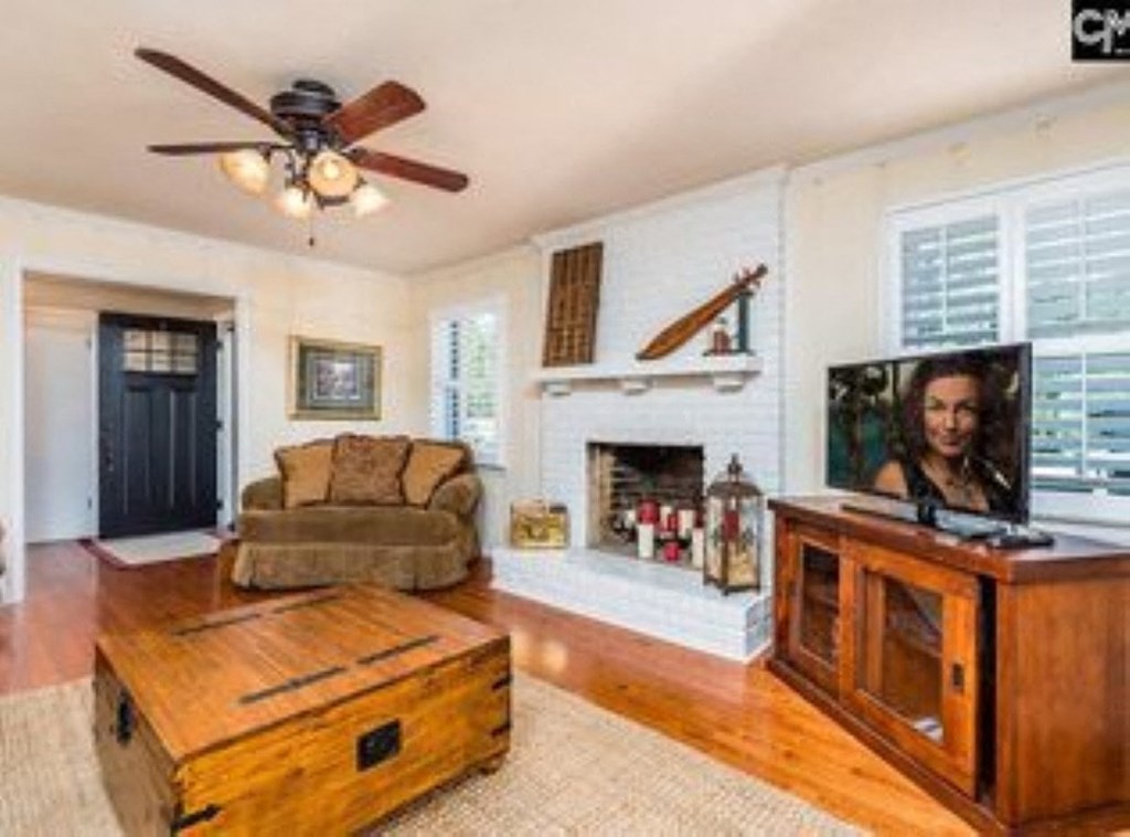A living room with a brown couch, a wooden coffee table, and a television on a wooden stand.