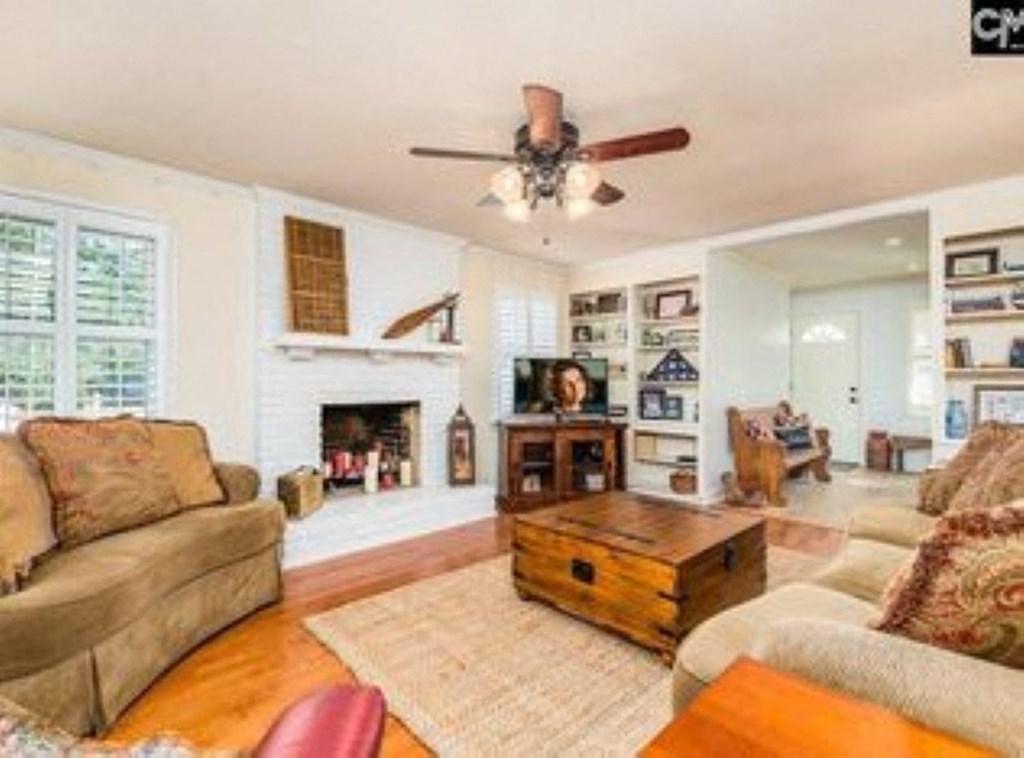 A living room with a fireplace, a couch, a coffee table, and a ceiling fan.