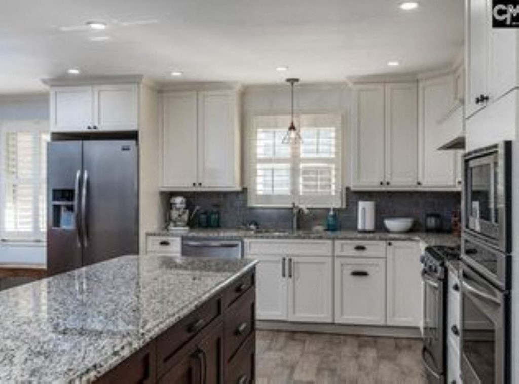 A kitchen with white cabinets and a granite countertop.