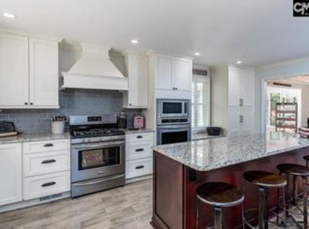 A kitchen with white cabinets and a large island with bar stools.