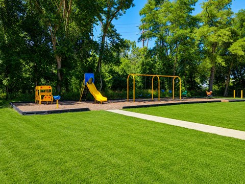A playground with a yellow slide and a blue sign.