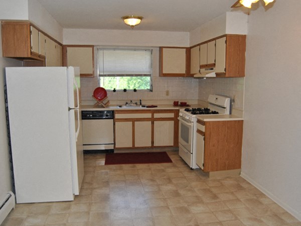 an empty kitchen with white appliances and wooden cabinets