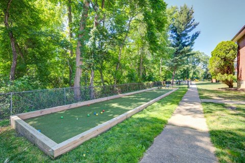 a backyard putting green with a fence and a sidewalk