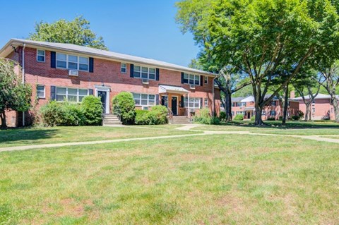 the front of a brick house with a lawn and trees