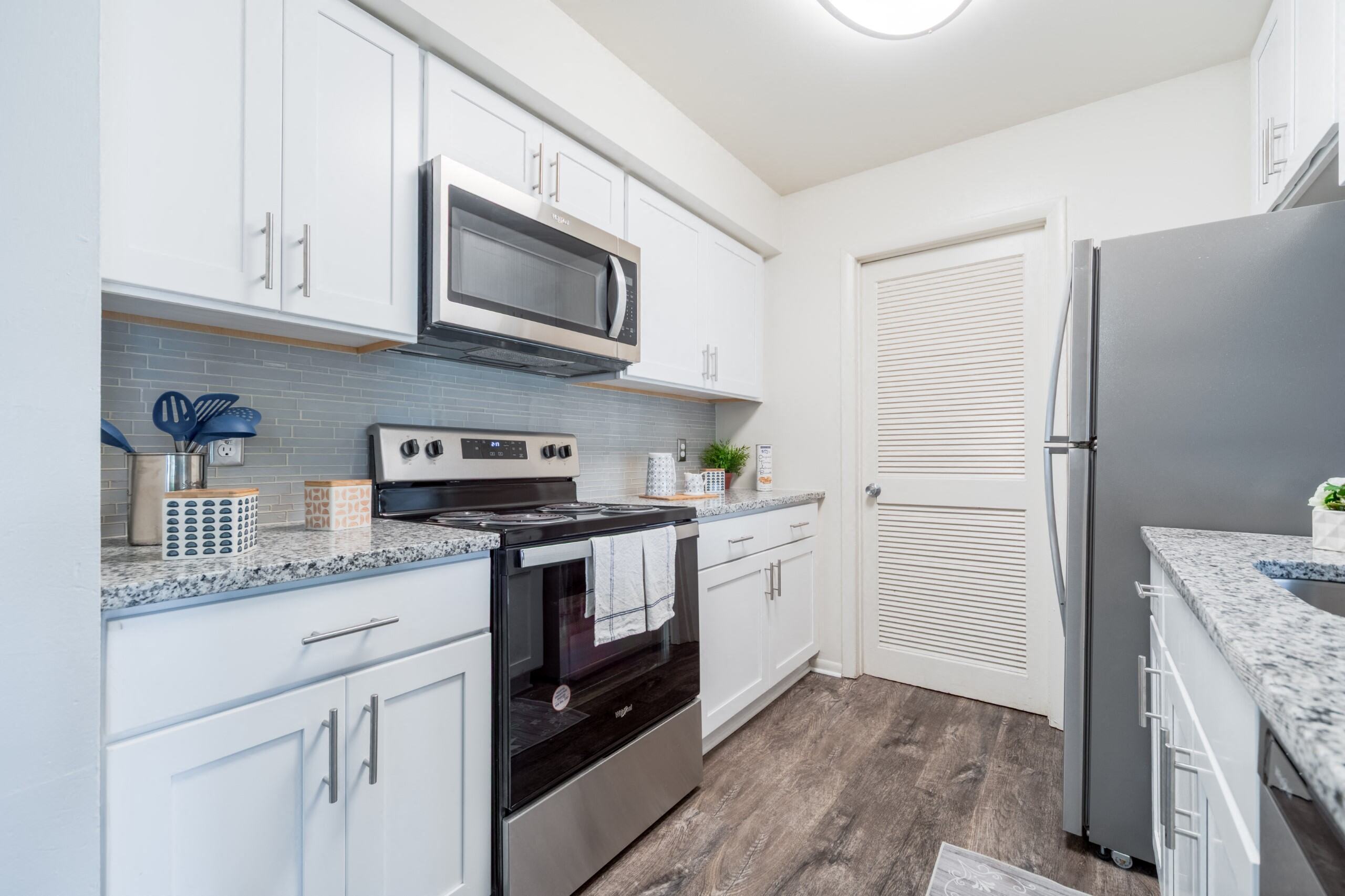 A kitchen with white cabinets and a black refrigerator.