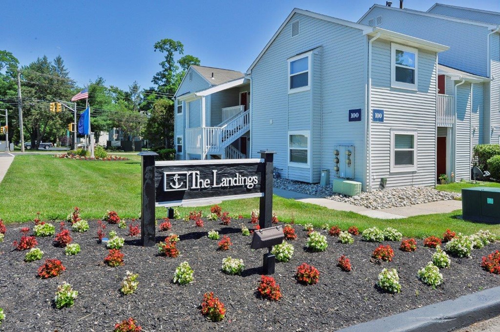 the landing apartments sign and flowers in front of buildings