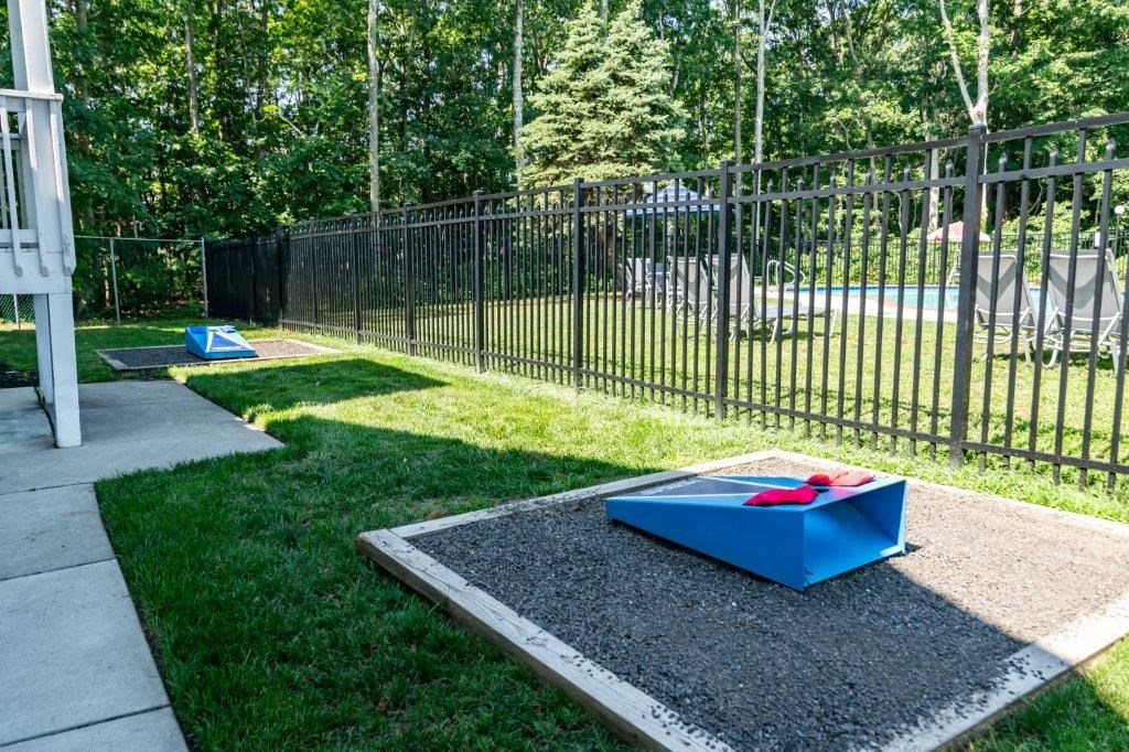 the playground is in front of a black fence and grass
