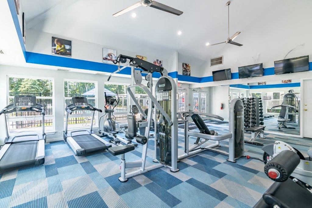 a gym with weights and cardio equipment in a room with windows