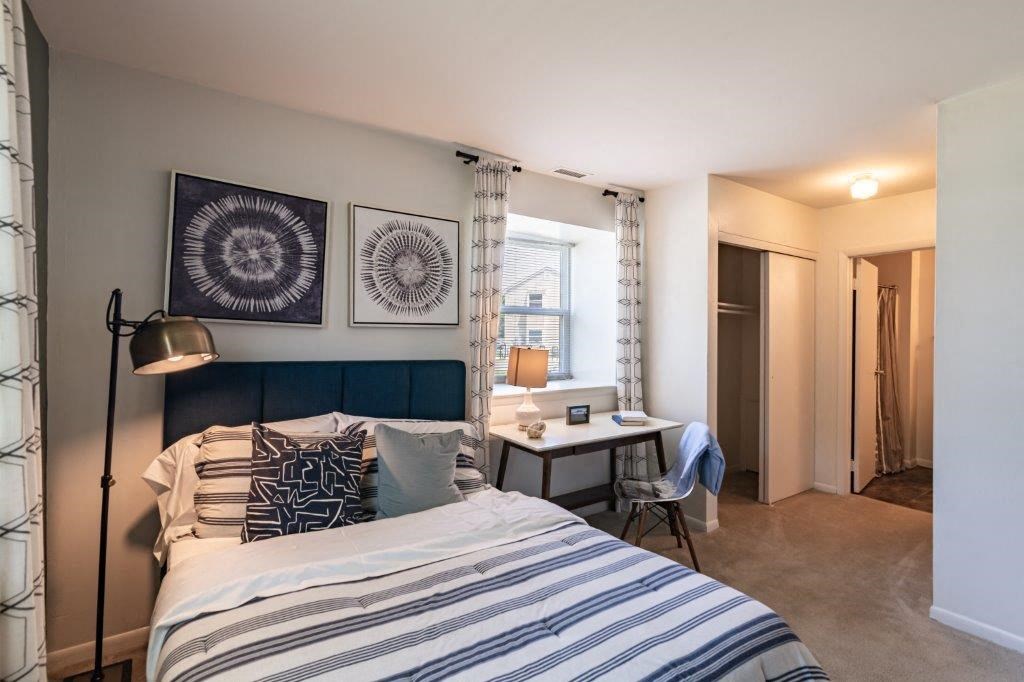 a bedroom with a bed and a desk and a window