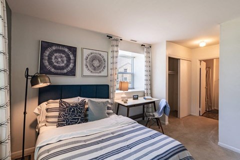 a bedroom with a bed and a desk and a window