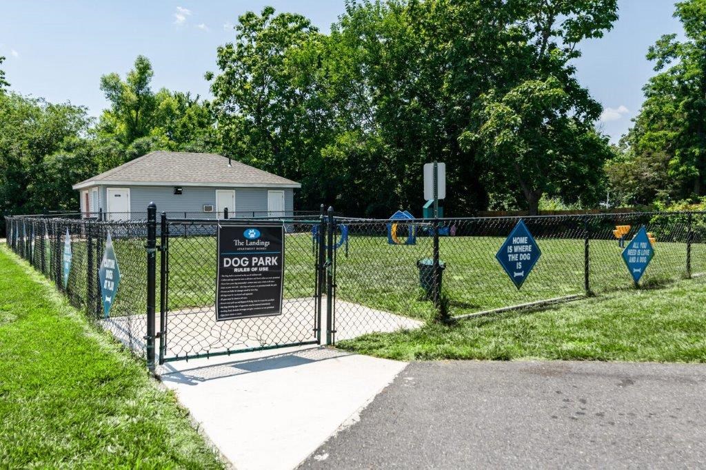 a dog park with a gate and a house behind it