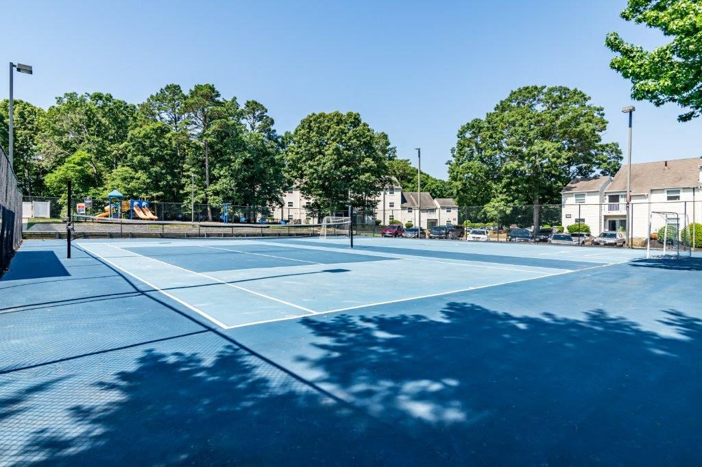 a tennis court with houses and trees in the background