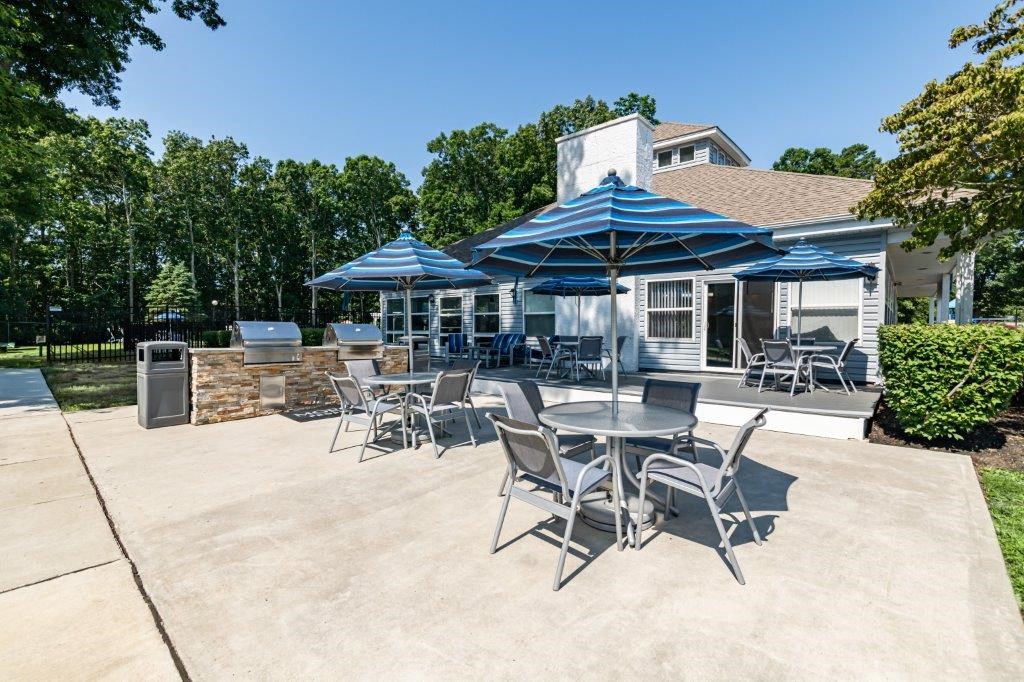 a patio with tables and umbrellas in front of a house