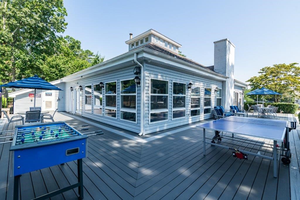 a large deck with a ping pong table and a white house