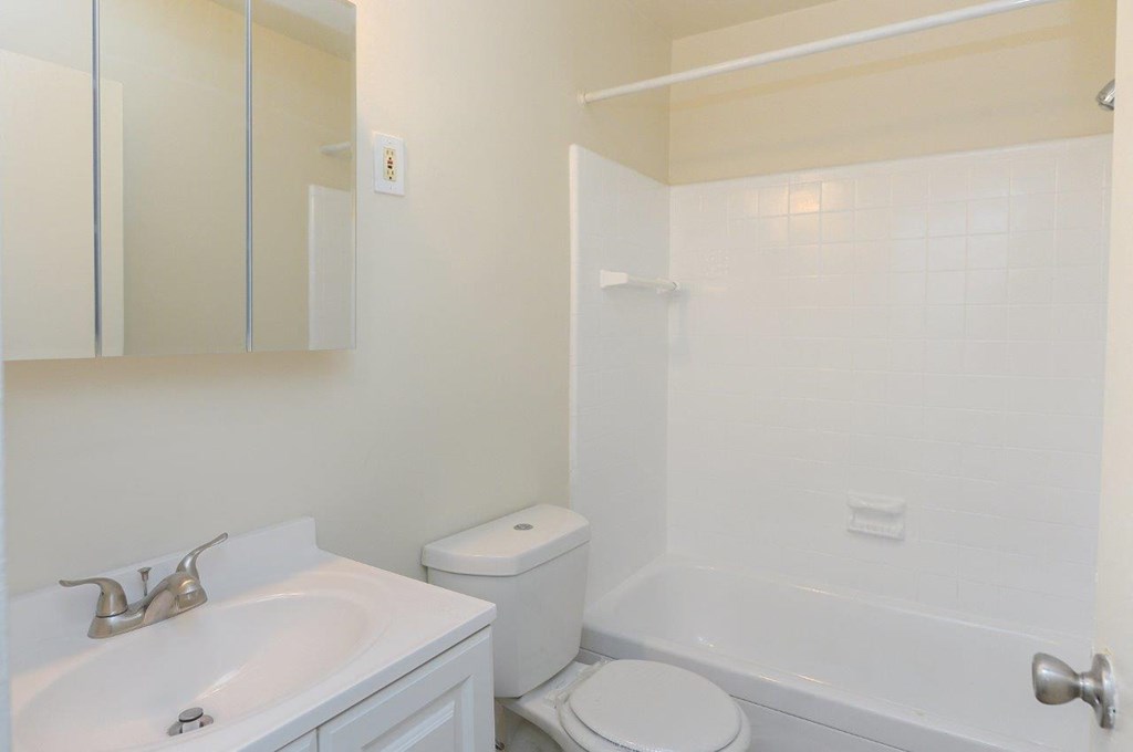 A white bathroom with a toilet, sink, and bathtub.