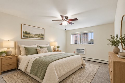 A bedroom with a bed, two lamps, a ceiling fan, and a painting on the wall.