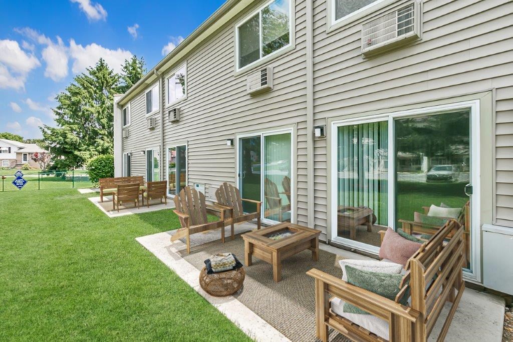 a backyard patio with wooden furniture and a house