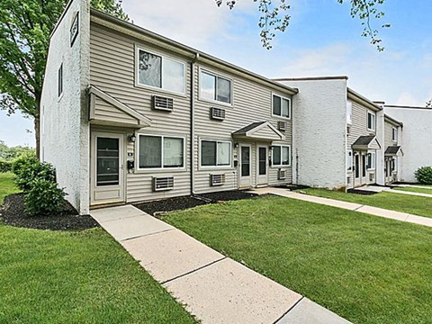 a white apartment building with a sidewalk and grass