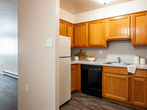 A kitchen with wooden cabinets and a black dishwasher.