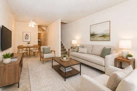A living room with a white couch, a wooden coffee table, and a painting on the wall.