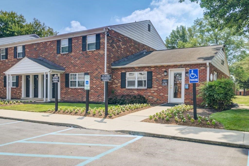 the front of a brick house with a sidewalk and parking lot